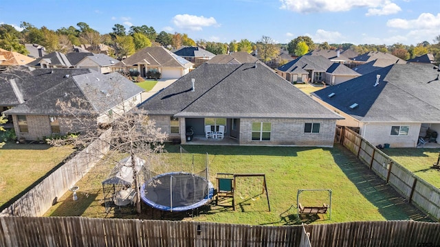 rear view of property featuring a playground, a yard, and a trampoline