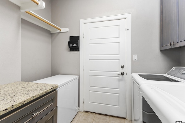 clothes washing area with separate washer and dryer and cabinets