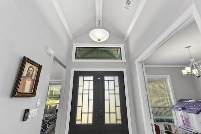 entrance foyer featuring a chandelier, lofted ceiling, and french doors