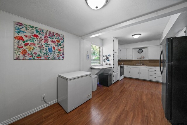 110 Utah St, Van, TX 75790 - kitchen with freestanding refrigerator, refrigerator, white range oven, dark wood-style floors, and white cabinetry