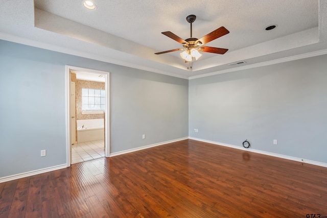 spare room featuring a raised ceiling, baseboards, and hardwood / wood-style floors