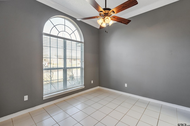 spare room with crown molding, baseboards, a ceiling fan, and light tile patterned flooring