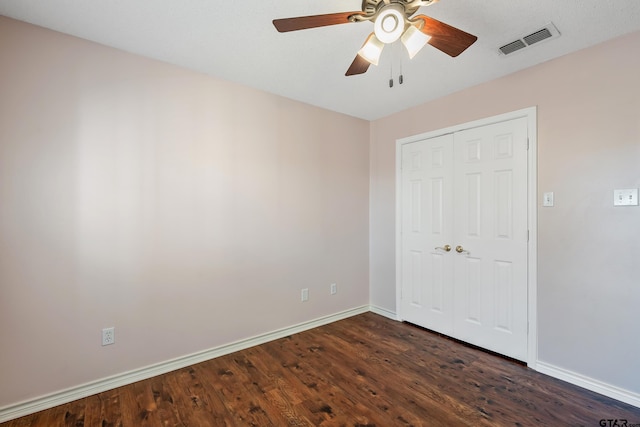 unfurnished bedroom featuring dark wood-style floors, a closet, visible vents, and baseboards