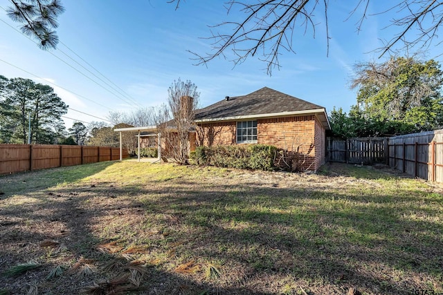 exterior space featuring brick siding, a lawn, and a fenced backyard