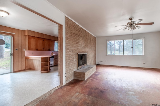 unfurnished living room with wooden walls, baseboards, a ceiling fan, light floors, and a fireplace