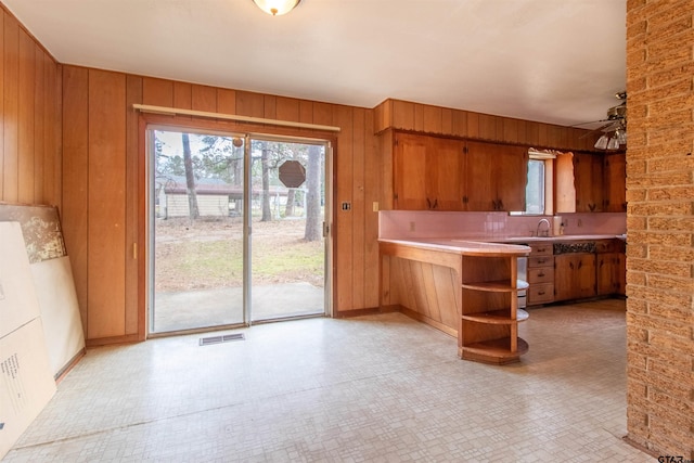 kitchen featuring wood walls, brown cabinetry, and visible vents