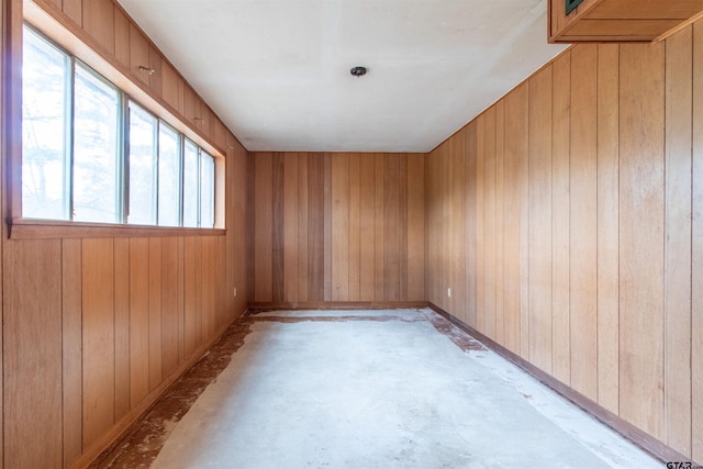 unfurnished room with wood walls and concrete floors