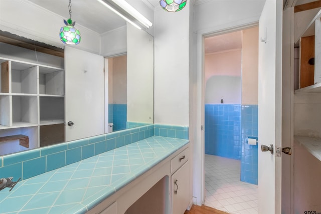 bathroom featuring tile patterned flooring, ornamental molding, tile walls, and vanity