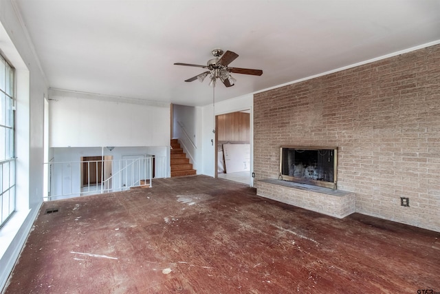 unfurnished living room featuring visible vents, brick wall, ceiling fan, stairway, and a fireplace