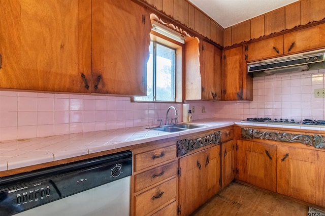 kitchen with decorative backsplash, stainless steel dishwasher, a sink, stovetop, and under cabinet range hood