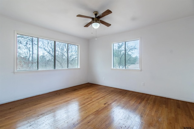 unfurnished room with wood-type flooring, a ceiling fan, and baseboards