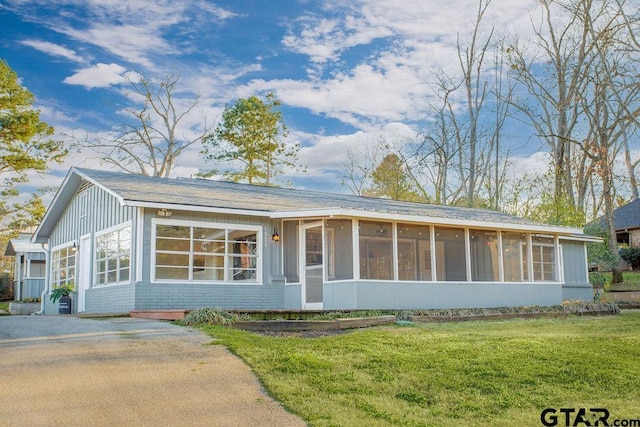 ranch-style house with brick siding, a front yard, and a sunroom