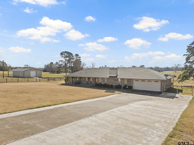 view of front of home with a front lawn, a rural view, and a garage