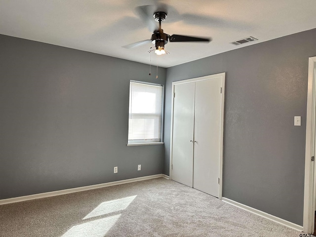 unfurnished bedroom featuring light carpet, ceiling fan, and a closet