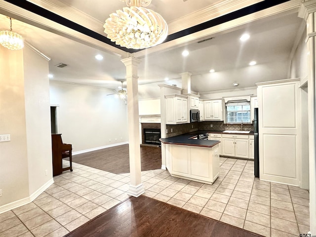 807 Brownwood Cir, Lindale, TX 75771 - kitchen featuring stainless steel microwave, a sink, decorative columns, dark countertops, and light tile patterned floors
