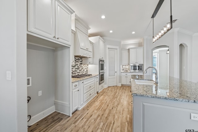 kitchen with hanging light fixtures, appliances with stainless steel finishes, sink, and white cabinets