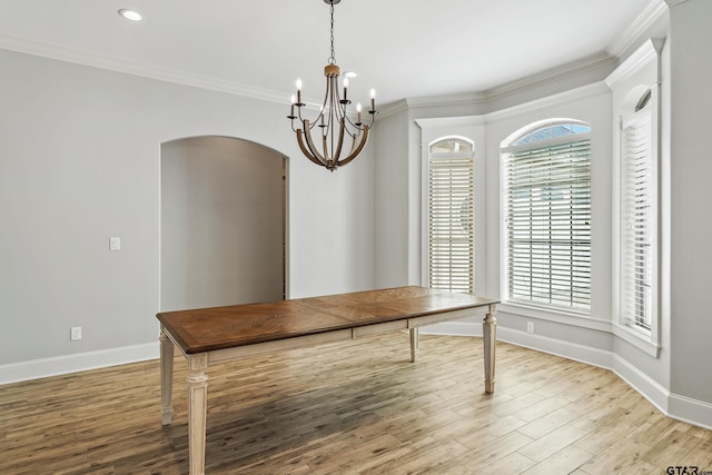 dining space featuring ornamental molding, a notable chandelier, and light wood-type flooring