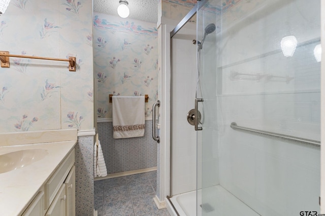 bathroom with vanity, a shower with shower door, and a textured ceiling