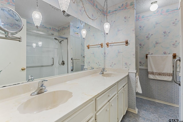 bathroom with tile patterned floors, a shower with door, vanity, and a textured ceiling