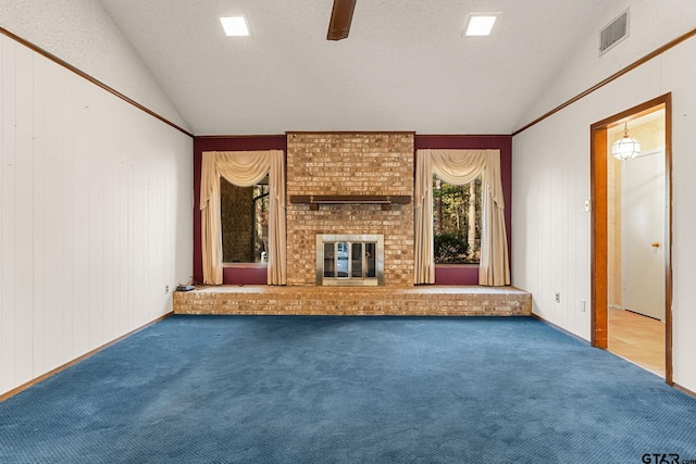 unfurnished living room featuring carpet, wood walls, a fireplace, and vaulted ceiling