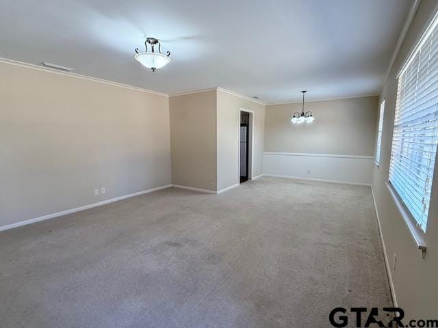 unfurnished room with ornamental molding, carpet, baseboards, and an inviting chandelier