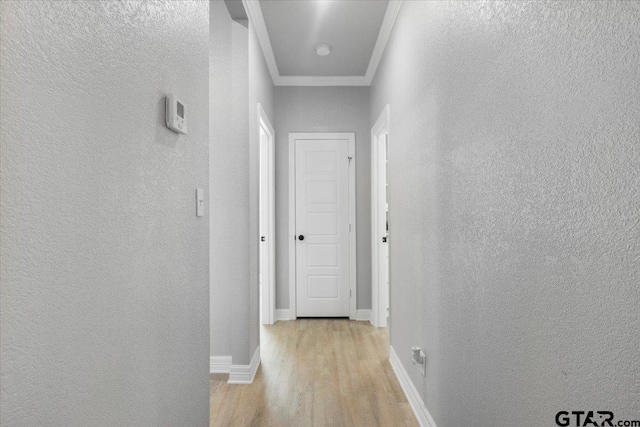 corridor with ornamental molding and light hardwood / wood-style floors