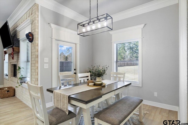 dining room with crown molding, light hardwood / wood-style flooring, and a large fireplace