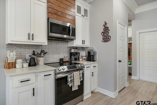 kitchen featuring backsplash, stainless steel appliances, ornamental molding, white cabinets, and light wood-type flooring