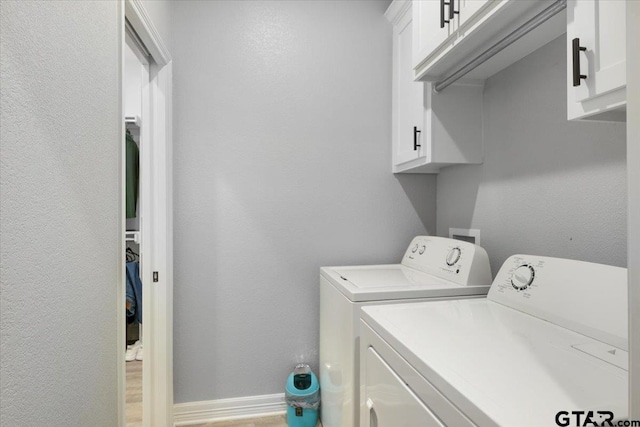 laundry area featuring washer and dryer, light hardwood / wood-style flooring, and cabinets