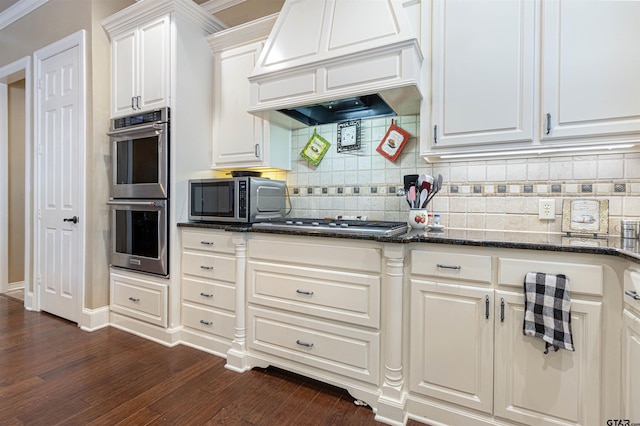 6530 Ashmore Ln, Tyler, TX 75703 - kitchen with stainless steel appliances, dark wood-style floors, white cabinets, tasteful backsplash, and premium range hood