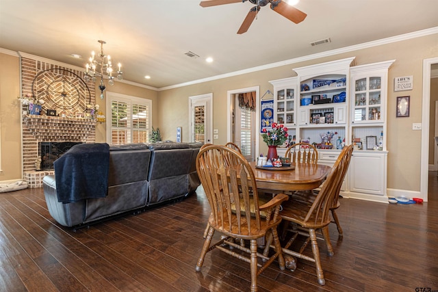 6530 Ashmore Ln, Tyler, TX 75703 - dining area featuring a brick fireplace, crown molding, dark wood-type flooring, a ceiling fan, and a chandelier