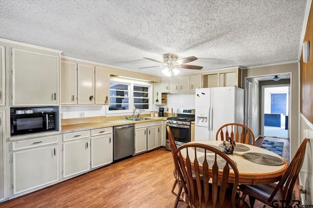 kitchen featuring crown molding, appliances with stainless steel finishes, a textured ceiling, sink, and light hardwood / wood-style floors