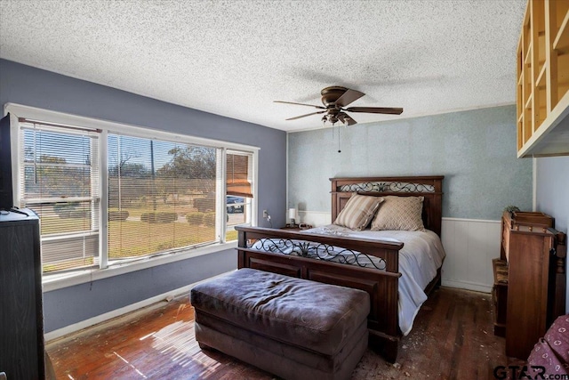 bedroom with a textured ceiling, dark hardwood / wood-style flooring, multiple windows, and ceiling fan