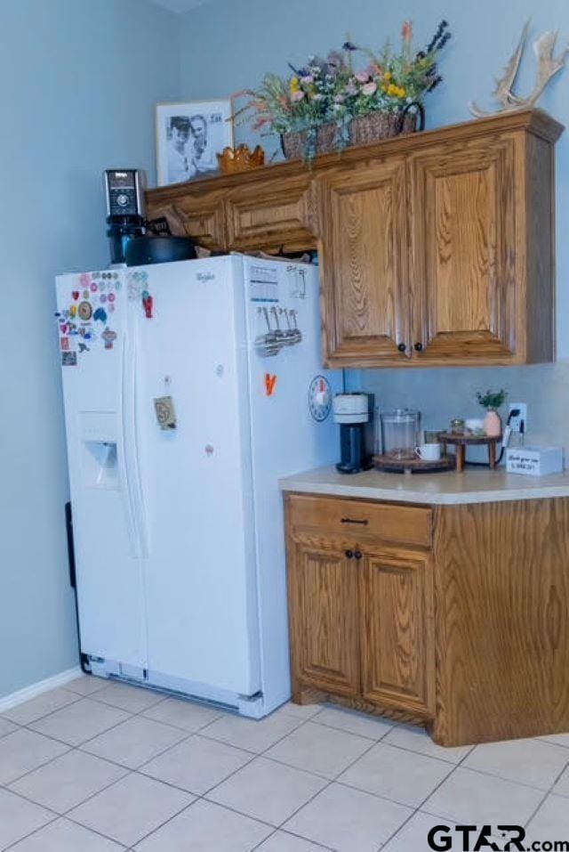 kitchen featuring white refrigerator with ice dispenser and light tile patterned floors