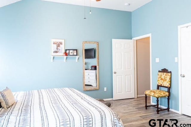 bedroom featuring vaulted ceiling, wood finished floors, and baseboards