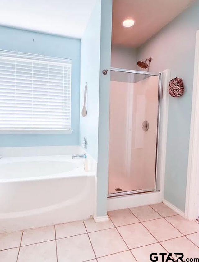 bathroom featuring tile patterned floors, a shower stall, baseboards, and a garden tub