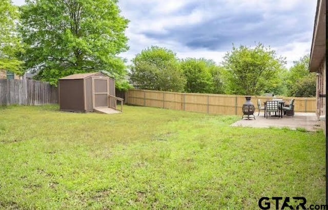 view of yard featuring a storage shed, an outdoor structure, a fenced backyard, and a patio