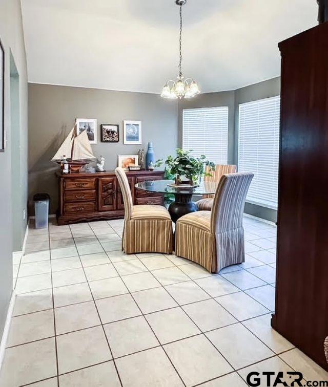 dining space with light tile patterned floors, lofted ceiling, and an inviting chandelier