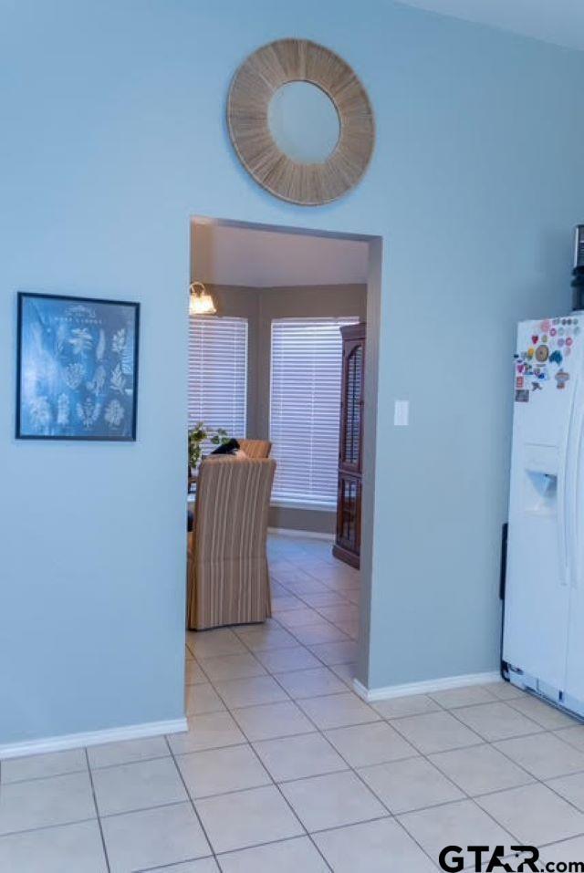 corridor with light tile patterned floors and an inviting chandelier