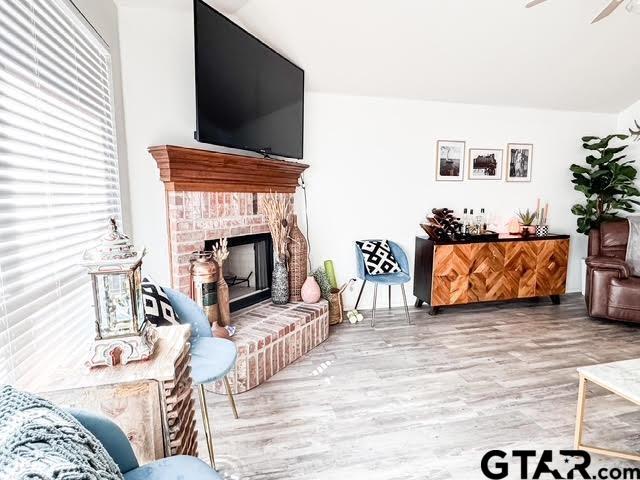 living room featuring hardwood / wood-style flooring, a brick fireplace, and ceiling fan