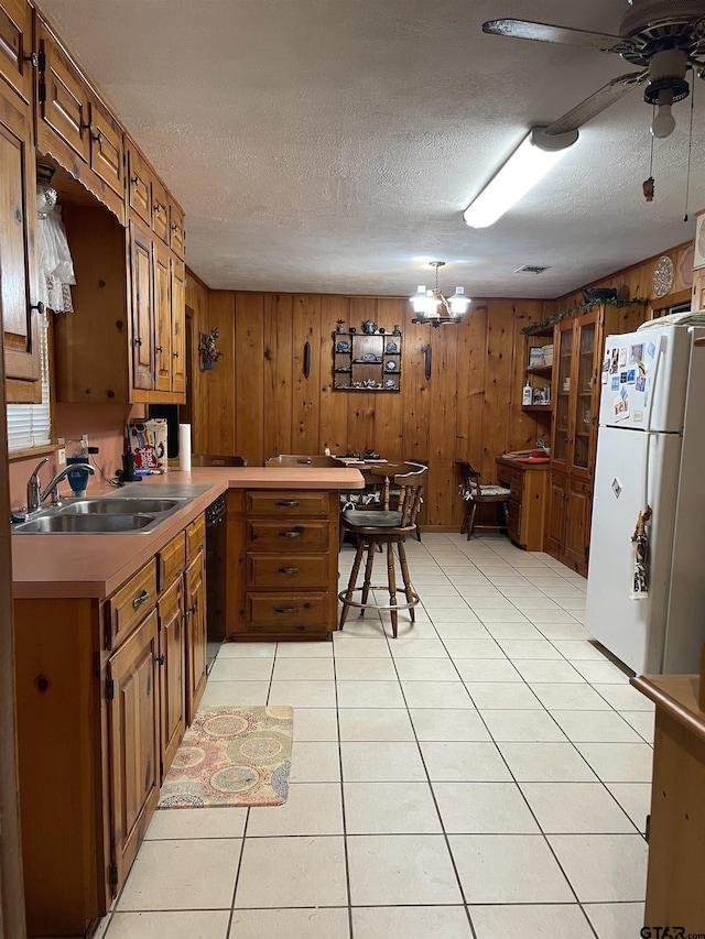 105 Walker Dr, Naples, TX 75568 - kitchen with black dishwasher, a sink, freestanding refrigerator, a peninsula, and brown cabinets