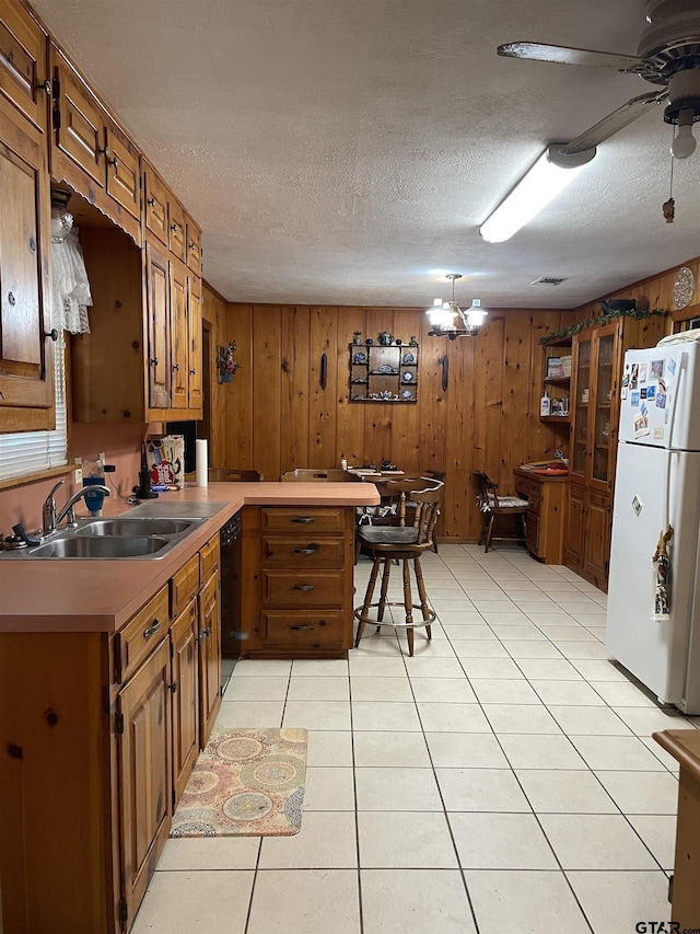 105 Walker Dr, Naples, TX 75568 - kitchen featuring wooden walls, freestanding refrigerator, brown cabinets, dishwasher, and a sink