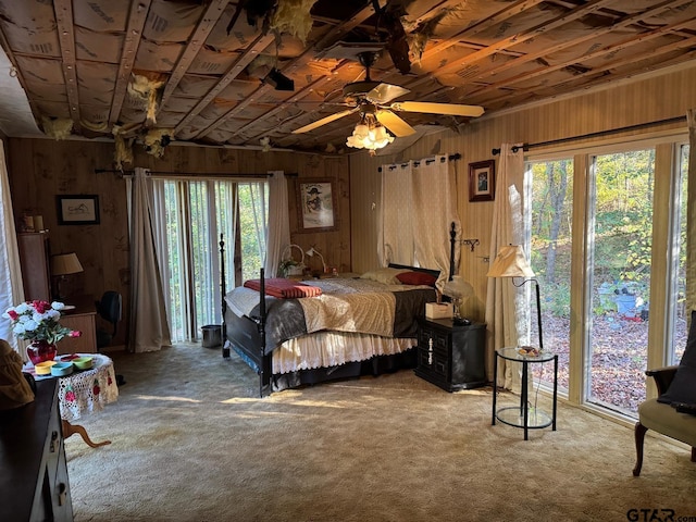 bedroom featuring carpet flooring, multiple windows, and wood walls