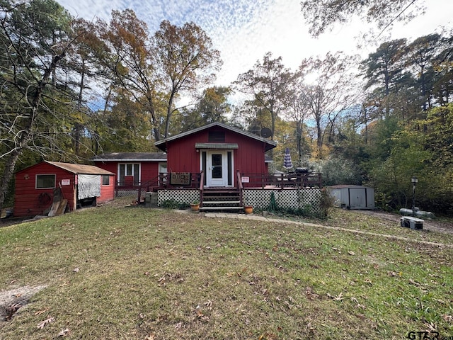 view of front of property with a shed, a deck, and a front lawn