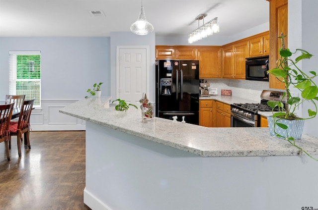 kitchen featuring kitchen peninsula, tasteful backsplash, light stone counters, black appliances, and decorative light fixtures