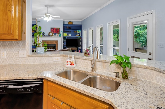 kitchen with light stone countertops, sink, a brick fireplace, black dishwasher, and crown molding