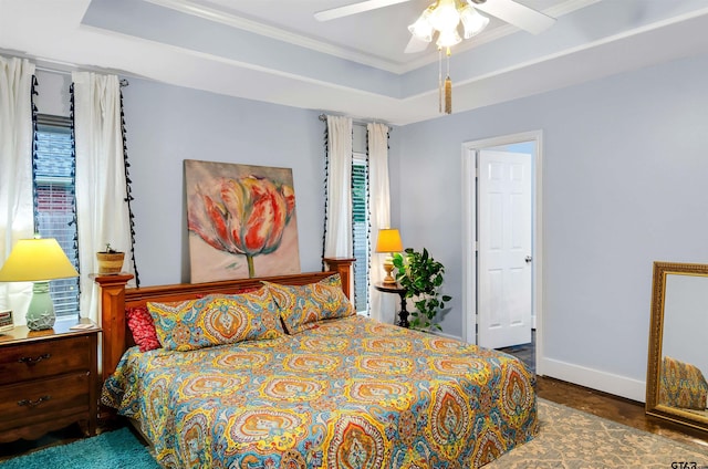 bedroom with ceiling fan, a raised ceiling, crown molding, and multiple windows