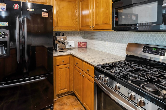 kitchen featuring backsplash, light stone countertops, and black appliances