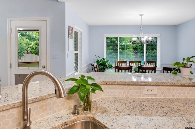 kitchen featuring light stone countertops, a chandelier, a healthy amount of sunlight, and decorative light fixtures