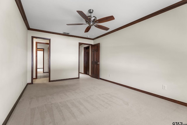 spare room with light carpet, ornamental molding, and ceiling fan